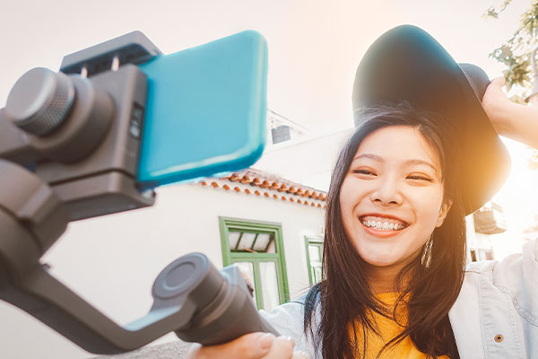 Junge Frau die lachend mit einem Smartphone auf einem Gimbal ein Selfie macht